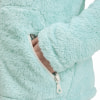 Eine Hand in den Taschen einer weichen mintgrünen Jacke, Reißverschlussdetail.
