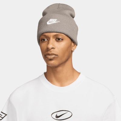 Ein Mann in einer grauen Nike-Mütze mit Logo und einem weißen T-Shirt mit Aufdruck. Ein Mann in einer grauen Nike-Mütze mit Logo und einem weißen T-Shirt mit Aufdruck.