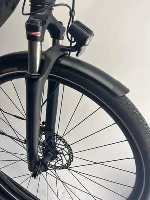 Vorderseite eines schwarzen E-Bikes mit Stoßdämpfer, Licht und Schutzblech.