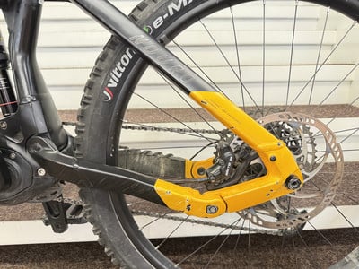 Das Hinterrad eines schwarzen E-Bikes mit orangefarbenem Rahmen und Scheibenbremse. Das Hinterrad eines schwarzen E-Bikes mit orangefarbenem Rahmen und Scheibenbremse.