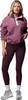 Eine Frau in einem rosafarbenen Fleece-Pullover und dunklen Leggings mit Turnschuhen.