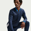 Ein Mann in einer dunkelblauen Nike-Jacke mit blauem Kragen und weißem Logo.