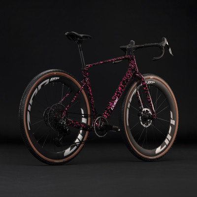 Ein rosa Cube-Fahrrad mit schwarzem Muster auf dem Rahmen vor schwarzem Hintergrund. Ein rosa Cube-Fahrrad mit schwarzem Muster auf dem Rahmen vor schwarzem Hintergrund.