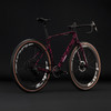 Ein rosa Cube-Fahrrad mit schwarzem Muster auf dem Rahmen vor schwarzem Hintergrund.