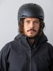Ein Mann in einem schwarzen Skihelm und einer Jacke blickt direkt in die Kamera.