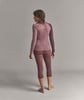 Eine Frau in einem rosafarbenen Langarmshirt und 3/4-Leggings.