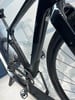 Schwarzer Carbon-Rahmen eines Rennrads mit Pedalen und Kette.