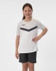 Ein Mädchen in einem weißen T-Shirt mit dunklem Streifen und schwarzen Shorts lächelt.