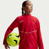 Mädchen in roter Jacke hält Fußball