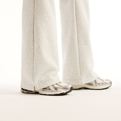 Damen-Jogginghosen in hellem Grau mit weiten Beinen und weißen Sneakern. Damen-Jogginghosen in hellem Grau mit weiten Beinen und weißen Sneakern.