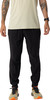 Mann in beige-farbenem Hemd und schwarzer Hose mit orangefarbenen Schuhen.