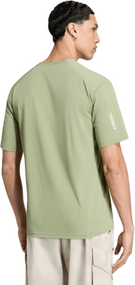 Mann in grünem T-Shirt mit TERREX-Aufschrift am Ärmel und beiger Hose. Mann in grünem T-Shirt mit TERREX-Aufschrift am Ärmel und beiger Hose.