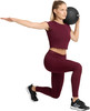 Eine Frau in Leggings macht einen Ausfallschritt mit einem Medizinball