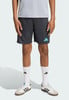 Chlapec má na sobě tmavě šedé šortky s tyrkysovými logy Adidas.