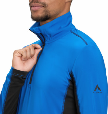 Ein Mann schließt eine blaue McKinley-Jacke mit schwarzen Details am Reißverschluss am Hals. Ein Mann schließt eine blaue McKinley-Jacke mit schwarzen Details am Reißverschluss am Hals.