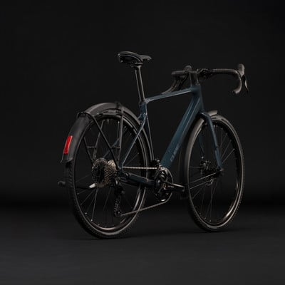 Dunkelblaues Gravelbike mit Schutzblechen und Gepäckträger vor schwarzem Hintergrund. Dunkelblaues Gravelbike mit Schutzblechen und Gepäckträger vor schwarzem Hintergrund.