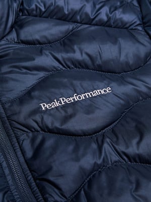 Detail einer dunkelblauen Steppjacke mit Peak Performance Logo. Detail einer dunkelblauen Steppjacke mit Peak Performance Logo.