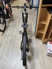 Ein Mountain-E-Bike steht auf einem Holzboden neben einem Regal.