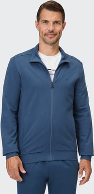 Ein Mann in einer blauen Reißverschlussjacke mit einem weißen T-Shirt darunter. Ein Mann in einer blauen Reißverschlussjacke mit einem weißen T-Shirt darunter.
