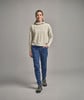 Eine Frau in einem beigen Hoodie und blauer Hose geht auf Sie zu.