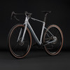 Graues Gravelbike mit braunen Reifen vor schwarzem Hintergrund.