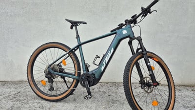 Ein grünes KTM E-Bike mit beigen Reifen steht vor einer Wand. Ein grünes KTM E-Bike mit beigen Reifen steht vor einer Wand.