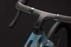 Detail eines modernen Carbonlenkers an einem Fahrrad mit blaugrünem Rahmen.