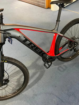 Graues Trek Mountain-E-Bike mit roten Akzenten und schwarzen Rädern. Graues Trek Mountain-E-Bike mit roten Akzenten und schwarzen Rädern.