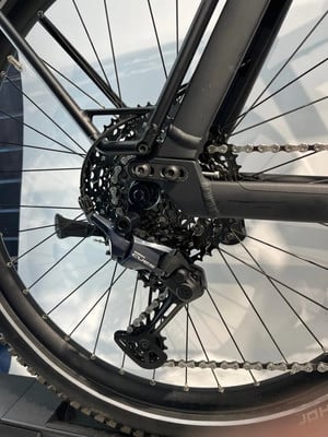 Detail des hinteren Schaltwerks und der Kassette an einem schwarzen Fahrrad.