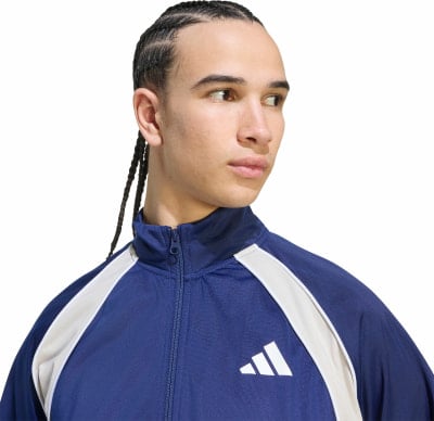 Mann in dunkelblauer Jacke mit weißen Streifen und Adidas-Logo. Mann in dunkelblauer Jacke mit weißen Streifen und Adidas-Logo.
