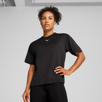 Eine Frau in einem schwarzen Puma-T-Shirt mit kurzen Ärmeln und Leggings steht.