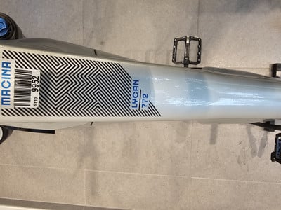 Ein silbernes Fahrrad mit schwarzem Muster auf dem Rahmen und dem Schriftzug MACINA.