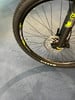 Detail eines Mountainbike-Rades mit Federgabel und Scheibenbremse auf blauem Teppich.