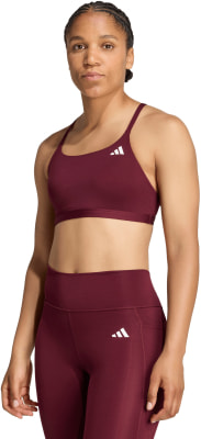 Eine Frau in einem dunkelroten Sport-BH und Leggings mit Adidas-Logo. Eine Frau in einem dunkelroten Sport-BH und Leggings mit Adidas-Logo.