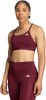 Eine Frau in einem dunkelroten Sport-BH und Leggings mit Adidas-Logo.