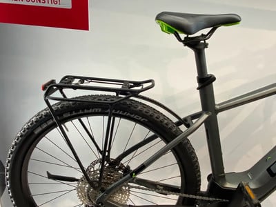 Rückseite eines grauen E-Bikes mit Gepäckträger und grünem Sattel. Rückseite eines grauen E-Bikes mit Gepäckträger und grünem Sattel.