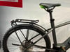 Rückseite eines grauen E-Bikes mit Gepäckträger und grünem Sattel.