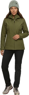 Eine Frau in grüner Jacke, schwarzer Hose und gestreifter Mütze posiert. Eine Frau in grüner Jacke, schwarzer Hose und gestreifter Mütze posiert.