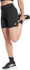Eine Frau in schwarzen Adidas-Shorts dehnt ihren Oberschenkel und trägt Sportschuhe.