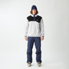 Ein Mann in Skibekleidung mit blauer Mütze und hellgrauem Fleece-Pullover.