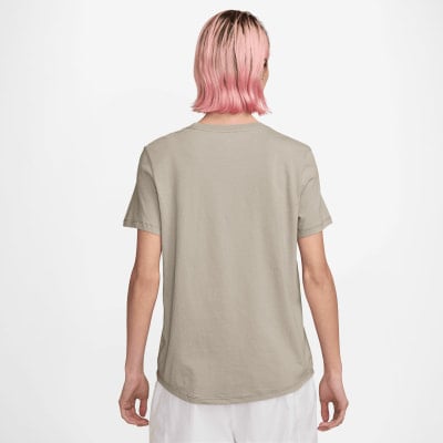 Rückansicht einer Frau mit pinken Haaren in einem beigen T-Shirt und weißer Hose.