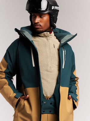 Ein Mann in einer Skijacke und einem Helm mit Brille blickt zur Seite. Ein Mann in einer Skijacke und einem Helm mit Brille blickt zur Seite.