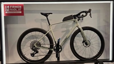 Ein hellgraues Cube Gravelbike mit schwarzem Lenker und Sattel auf einem Ständer. Ein hellgraues Cube Gravelbike mit schwarzem Lenker und Sattel auf einem Ständer.
