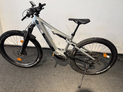 Ein E-Mountainbike mit Federung und breiten Reifen steht auf einem Teppich. Ein E-Mountainbike mit Federung und breiten Reifen steht auf einem Teppich.