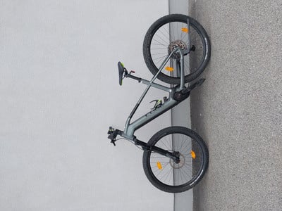 Graues Mountainbike, das an einer Wand mit Steintextur lehnt.