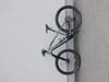 Graues Mountainbike, das an einer Wand mit Steintextur lehnt.