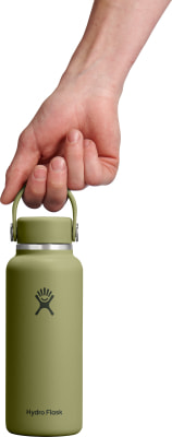 Eine Hand hält eine grüne Hydro Flask Flasche am Griff. Eine Hand hält eine grüne Hydro Flask Flasche am Griff.