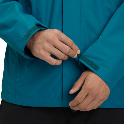 Ein Mann schließt den Klettverschluss am Ärmel einer türkisfarbenen Jacke. Ein Mann schließt den Klettverschluss am Ärmel einer türkisfarbenen Jacke.
