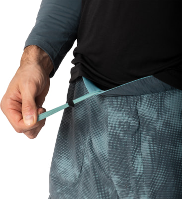 Ein Mann zieht die Kordel einer grauen Hose mit Muster fest. Ein Mann zieht die Kordel einer grauen Hose mit Muster fest.