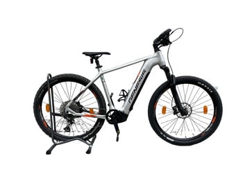 Silbernes E-Bike auf einem Ständer mit schwarzen Reifen und orangefarbenen Details.